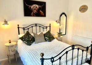 ein Schlafzimmer mit einem Bett mit einem Kuhgemälde an der Wand in der Unterkunft 18th Century Cosy Cottage with Stunning views in Stratford in Stratford-upon-Avon