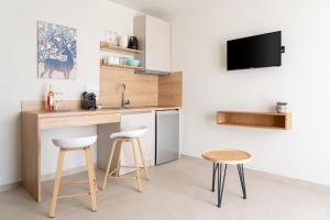 a kitchen with a counter and two stools and a tv at GeoMar Luxury Apartments in Skala Marion