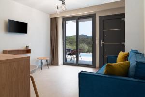 a living room with a blue couch and a sliding glass door at GeoMar Luxury Apartments in Skala Marion