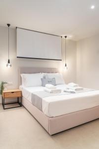 a white bedroom with a large bed with a projector screen at GeoMar Luxury Apartments in Skala Marion