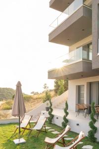 a patio with chairs and an umbrella in front of a building at GeoMar Luxury Apartments in Skala Marion