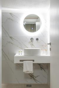 a white bathroom with a sink and a mirror at GeoMar Luxury Apartments in Skala Marion