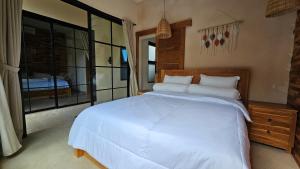a bedroom with a large white bed and a window at LM Home Mendira in Candidasa +29 photos