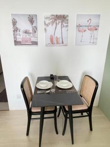 een zwarte tafel met twee stoelen en foto's aan de muur bij Freedom Flamingos-RoxyBeachApt in Sematan
