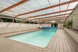 an indoor swimming pool with a glass roof at Demeures & Châteaux Le Clos Luly in Neulliac