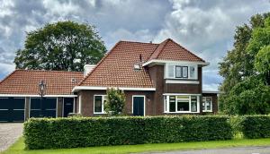 a brick house with a red roof at De Pastorij, heerlijke rustgevende plek tussen de koeien! in Hornsterzwaag