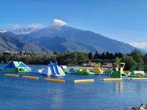 a row of inflatable slides on a lake with a mountain at Penthouse en bleu royal in Vinça