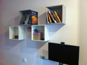 a wall with three shelves with books and a computer monitor at Casa Vacanze Orchidea CIR0347AT00249 in Parma