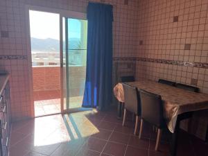 a kitchen with a table with chairs and a window at Complexe tarifa in Tangier