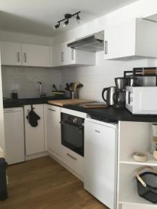 a kitchen with white cabinets and black counter tops at Appartement idéalement situé in Les Sables-dʼOlonne