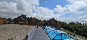 a wooden boardwalk with a playground with wooden huts at Grey Sea Rusinowo in Rusinowo