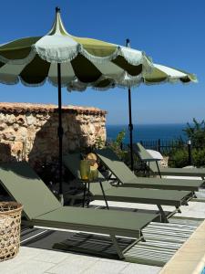 a row of lounge chairs and an umbrella on a patio at Villa Casa Nova in Balchik
