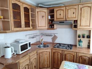 eine Küche mit Holzschränken, Spüle und Mikrowelle in der Unterkunft Sofi 2-комнатный in Narva