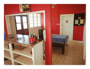a kitchen with red walls and a table and a bed at Swartkops Cann-a-bee Air B&B in Gqeberha