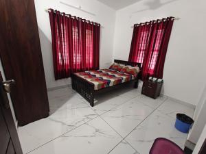 a bedroom with a bed and two red curtains at Aadhi Villa in Varkala