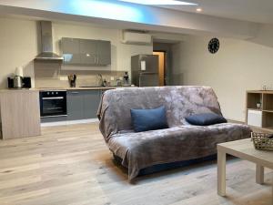 a living room with a couch and a kitchen at Joli petit appartement in Eymet