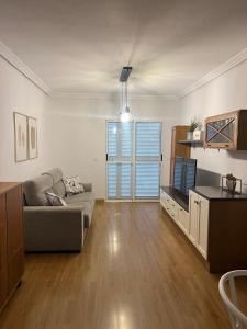 a living room with a couch and a tv at Piso con AC, piscina y pista de pádel y tenis en Águilas in Águilas