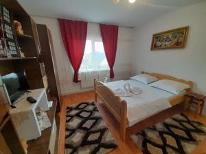 ein Schlafzimmer mit einem Bett und einem Fenster mit roten Vorhängen in der Unterkunft Cabana Robert in Arieşeni