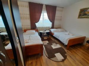 ein Schlafzimmer mit zwei Betten und einem Tisch und einem Fenster in der Unterkunft Cabana Robert in Arieşeni