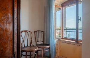 two chairs and a window with a view of the water at Fiammetta in Rovinj