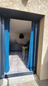 an open door to a kitchen with blue curtains at La Voûte - Maison de charme in Saint-Clair