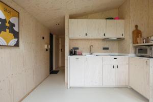 ヴェストカペレにあるHello Zeeland - Tiny House Zeeuwse Liefde 15の白いキャビネットと電子レンジがある空のキッチン