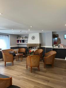 a waiting room with chairs and tables and a fireplace at Hotel Atlantique in Le Palais