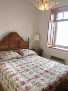 a bedroom with a bed with a comforter and a window at Quinta do galo in Magrelos