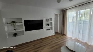 a white living room with a flat screen tv on a wall at Odiseea Apartment-Private parking included in Sibiu