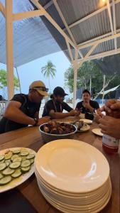 Un gruppo di uomini seduti a tavola che mangiano cibo di Juita Glamping Perhentian island a Isole Perhentian Altre 24 foto
