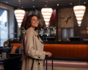 Una mujer con una gabardina sosteniendo una maleta en Boutique Hotel Germania, en Múnich