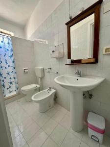 a white bathroom with a sink and a toilet at Hotel Giglio in Lampedusa