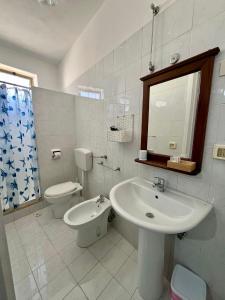 a white bathroom with a sink and a toilet at Hotel Giglio in Lampedusa