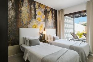 2 Betten in einem Hotelzimmer mit Blumen an der Wand in der Unterkunft Villa María in Playa Blanca + 59 Fotos