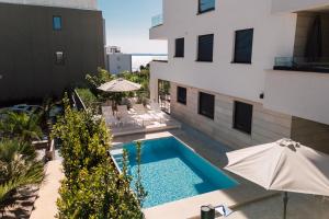 an apartment with a swimming pool and two umbrellas at Adria Concept Suites in Zadar