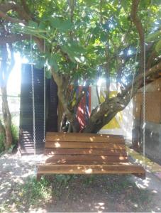 a wooden bench chained to a tree in a yard at Serenity Village Cottage with outside toilet in Balabani +2 photos