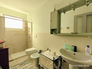 ein Badezimmer mit Waschbecken, Toilette und Spiegel in der Unterkunft Mamma Assuntina in Lecce