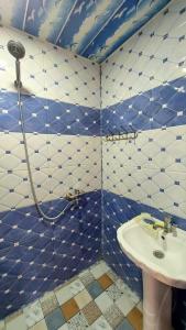 Baño de azulejos azules y blancos con lavabo en Laza guest house mi, en Laza