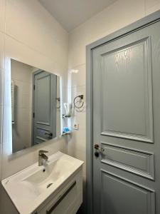 a bathroom with a sink and a mirror and a door at Aparthotel Kutaisi in Kutaisi +73 photos