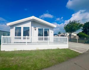 a small white house with a white fence at 2 Lakeside, Luxury lodge with private garden & parking in Patrington