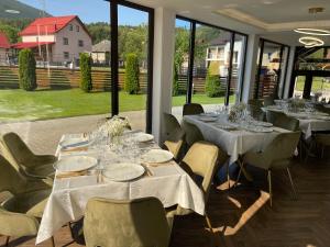 a dining room with tables and chairs and windows at Casa Belvedere Pietrosu in Moisei