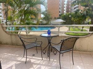 a table and two chairs on a balcony with a pool at Alcaravanes 1 in Higuerote