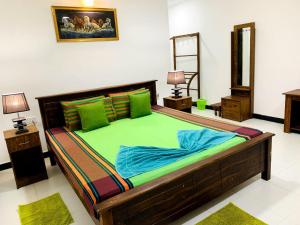 una camera da letto con un grande letto in legno con lenzuola verdi di Sigiri Prabha Villa a Sigiriya