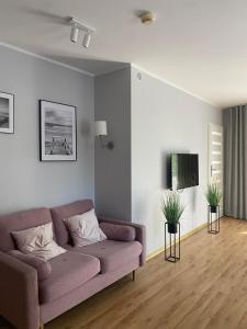 a living room with a purple couch and a tv at Apartament Olymp 113 z dwoma sypialniami i basenem in Kołobrzeg