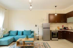 a living room with a blue couch and a kitchen at Feel Like home appartment in Xanthi