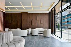 a lobby with white chairs and tables and a large window at Neo by Wynwood House in Bogotá