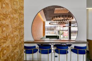 a bar with blue stools in front of a mirror at Neo by Wynwood House in Bogotá