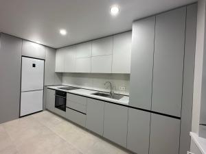 a kitchen with white cabinets and a sink and a refrigerator at Apartament nou in Căuşeni