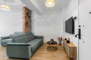 ein Wohnzimmer mit einer blauen Couch und einem Fernseher in der Unterkunft Chill Side - Infinity Pool & Spa Resort in Mamaia Nord – Năvodari