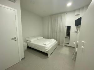 Un dormitorio blanco con una cama y un televisor. en B&B Loretta, en Marcianise